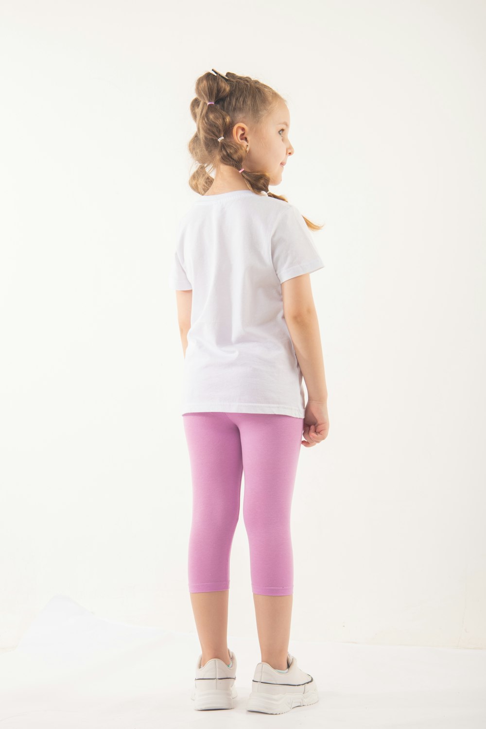 A little girl in a white shirt and pink leggings photo – Free