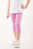 A person wearing a white top and pastel pink leggings is standing with one hand on their hip. The footwear is a pair of white sneakers with shiny details. The background is a plain, light color.