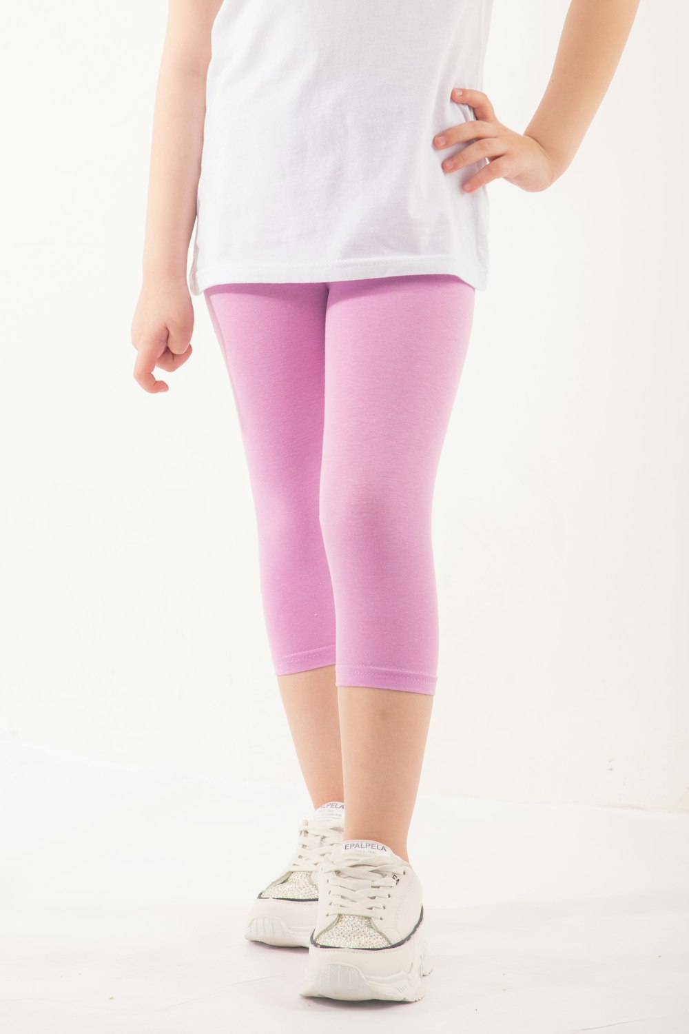 a little girl in a white shirt and pink leggings
