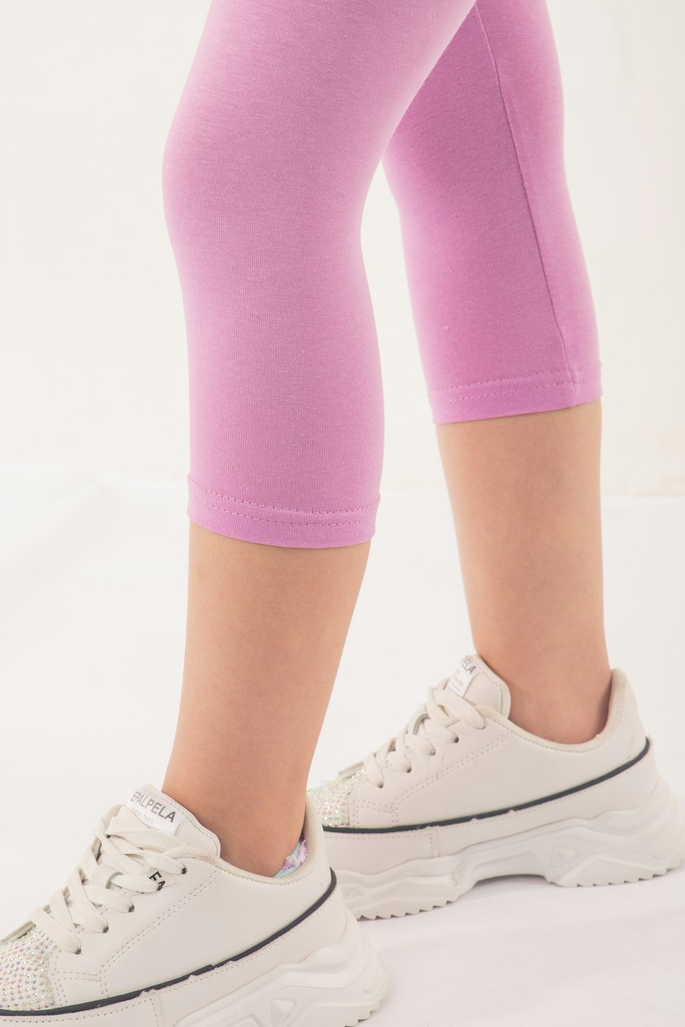 a close up of a person's legs wearing white sneakers