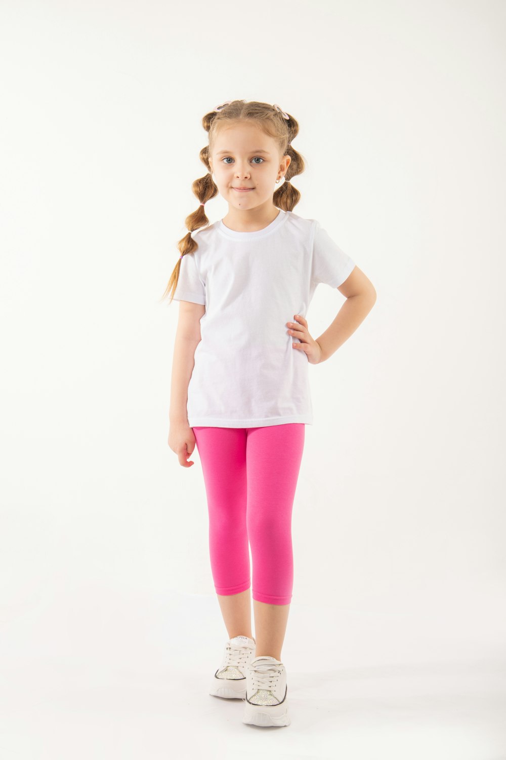 a little girl in a white shirt and pink leggings