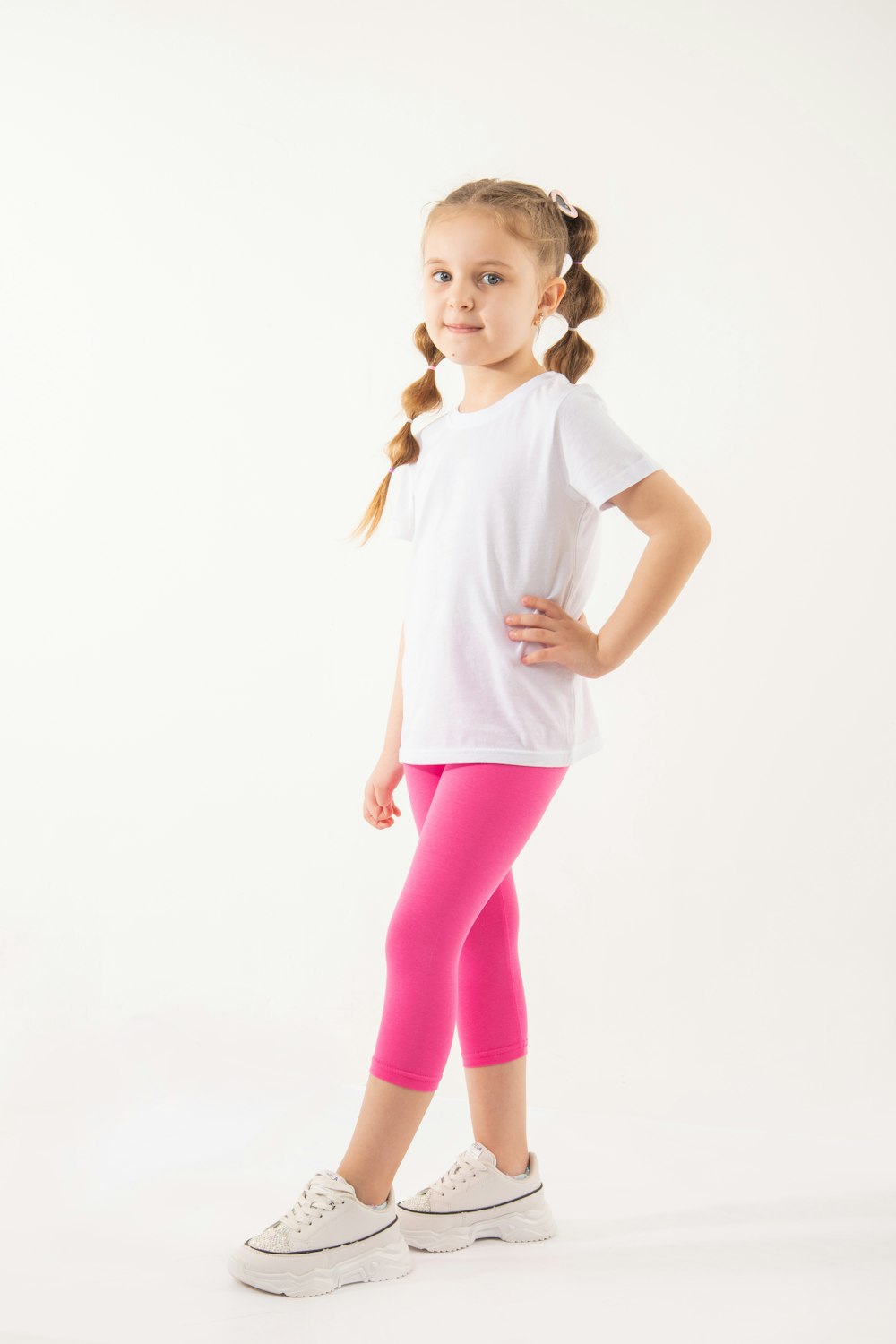 a little girl in a white shirt and pink leggings