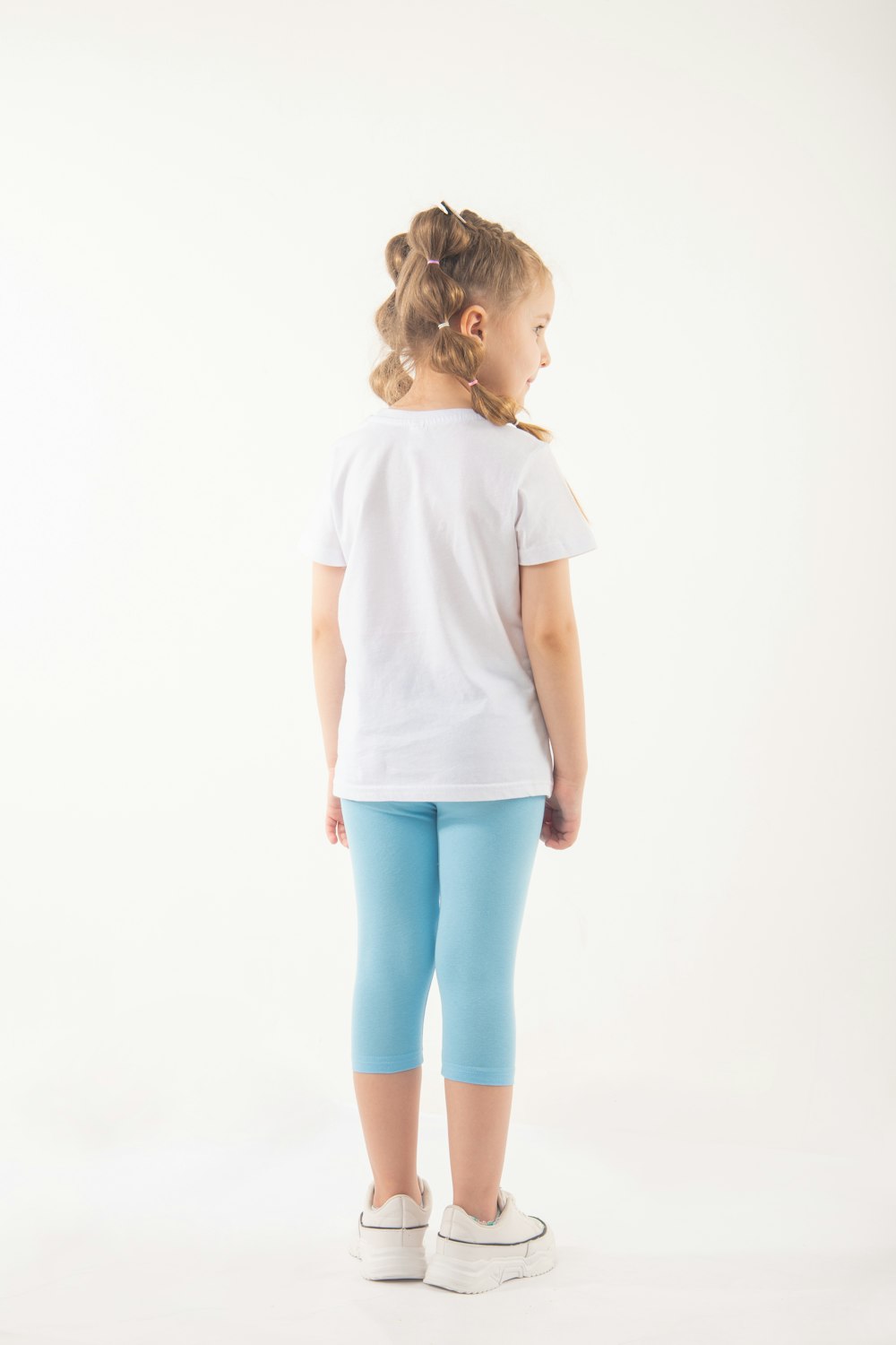 a little girl wearing blue leggings and a white t - shirt