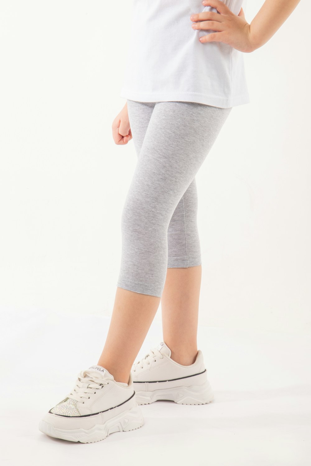 a little girl in a white shirt and grey leggings
