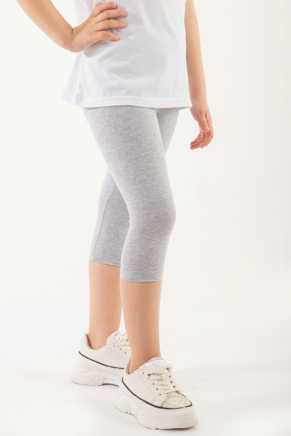 a little girl in a white shirt and grey leggings