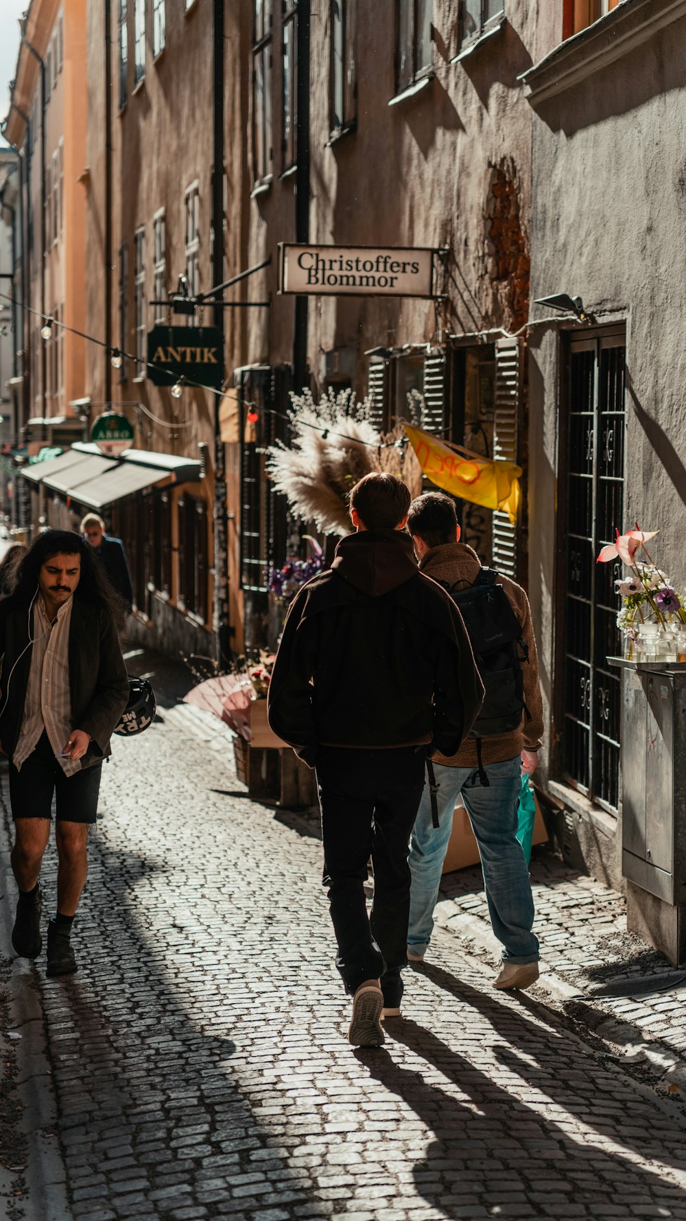 a group of people walking down a street next to tall buildings