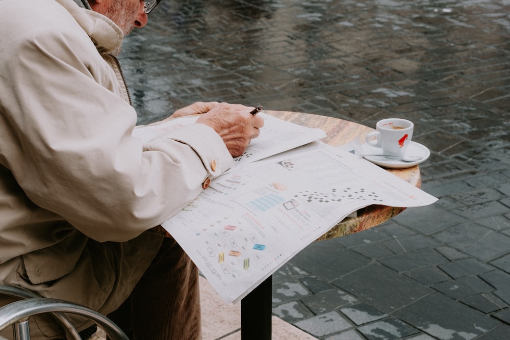 a man sitting at a table writing on a piece of paper