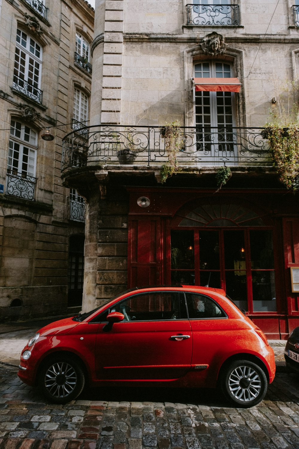 a small red car parked in front of a building