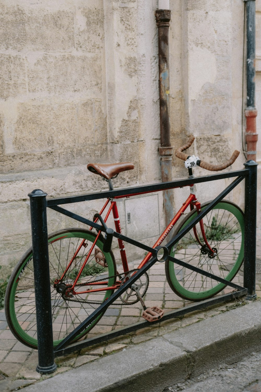 a bicycle locked to a metal fence on a sidewalk