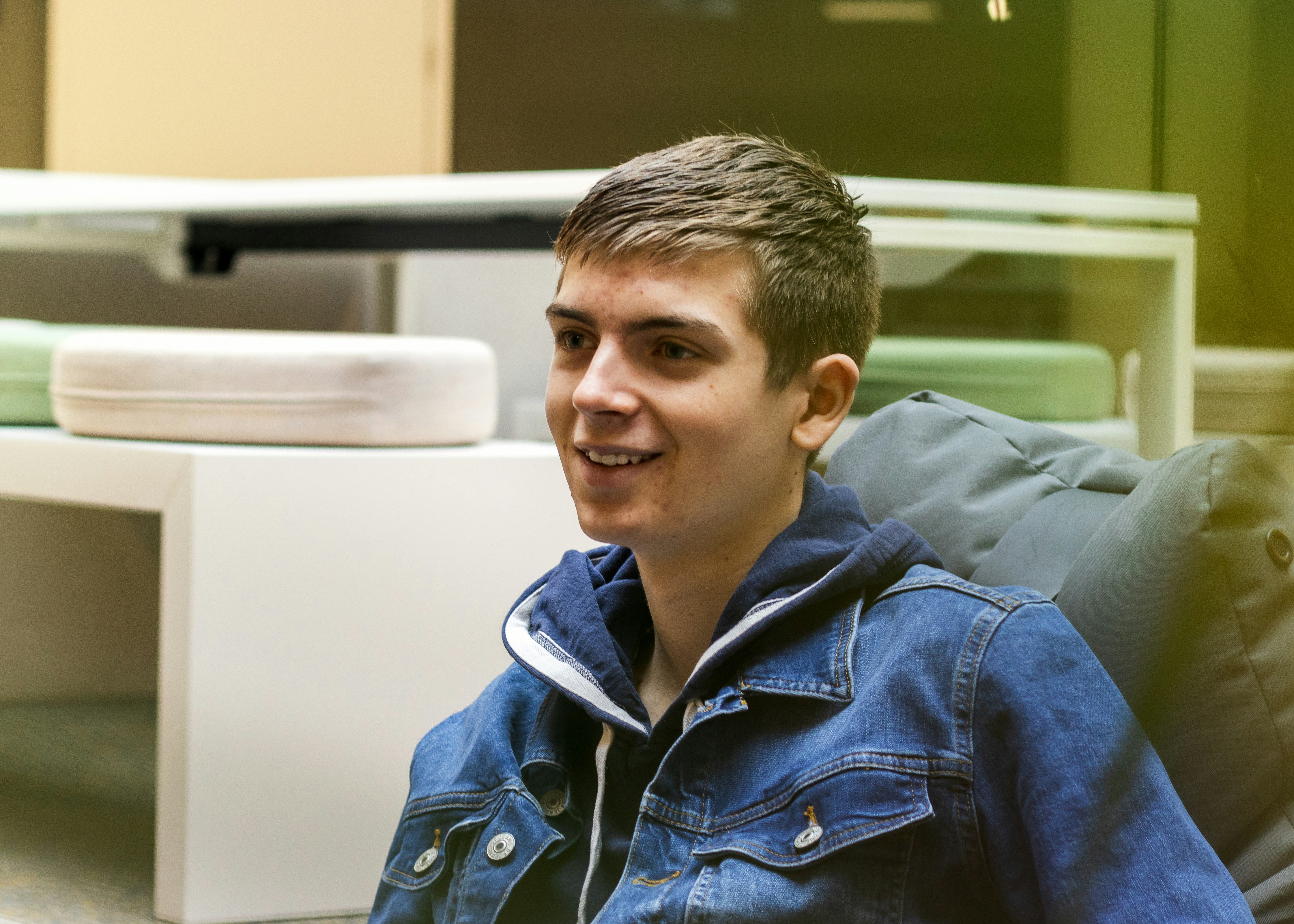 a young man sitting in a chair with a blue jacket on