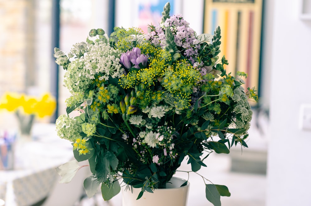 a vase filled with lots of green and white flowers