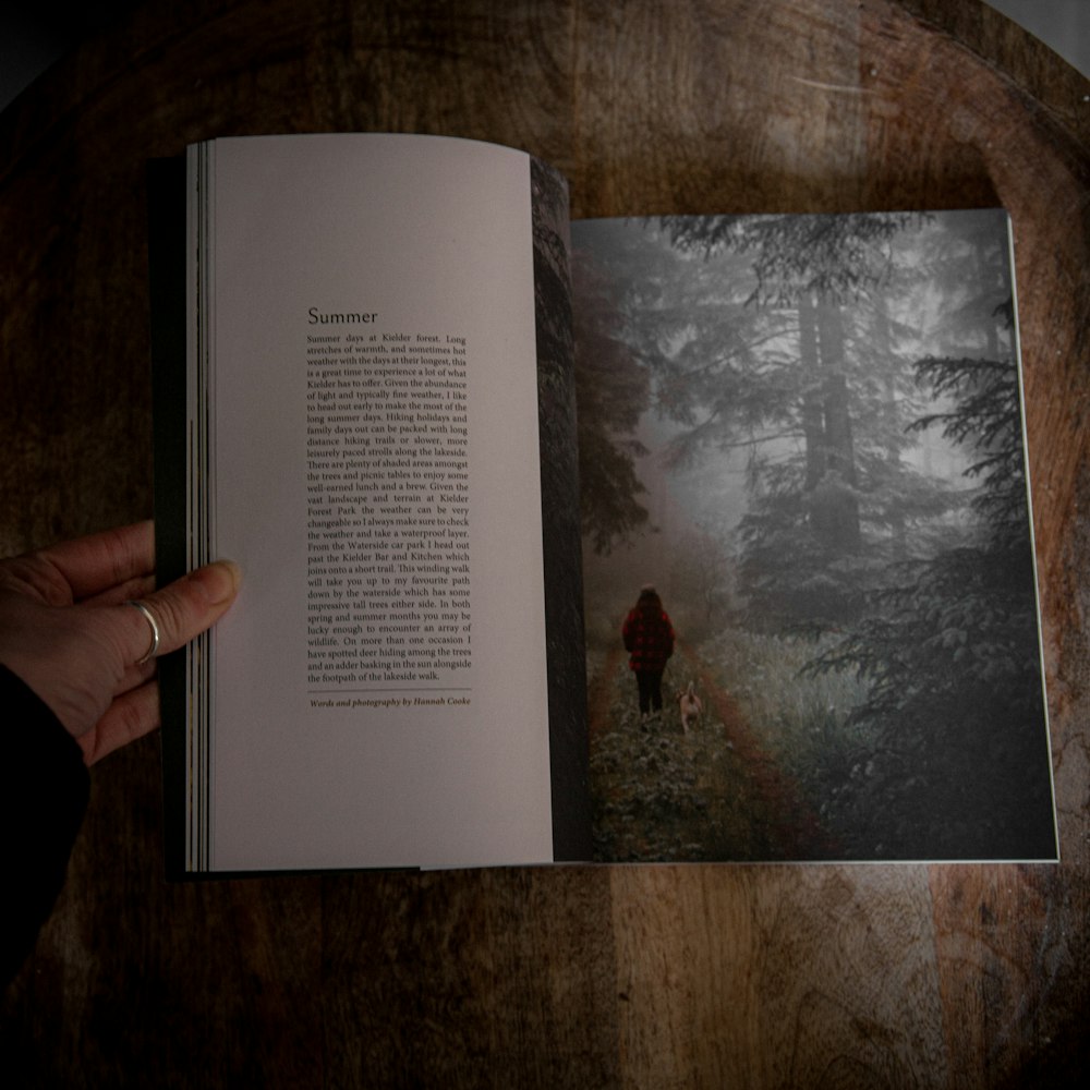 a person holding a book open to a picture of a person walking in the woods