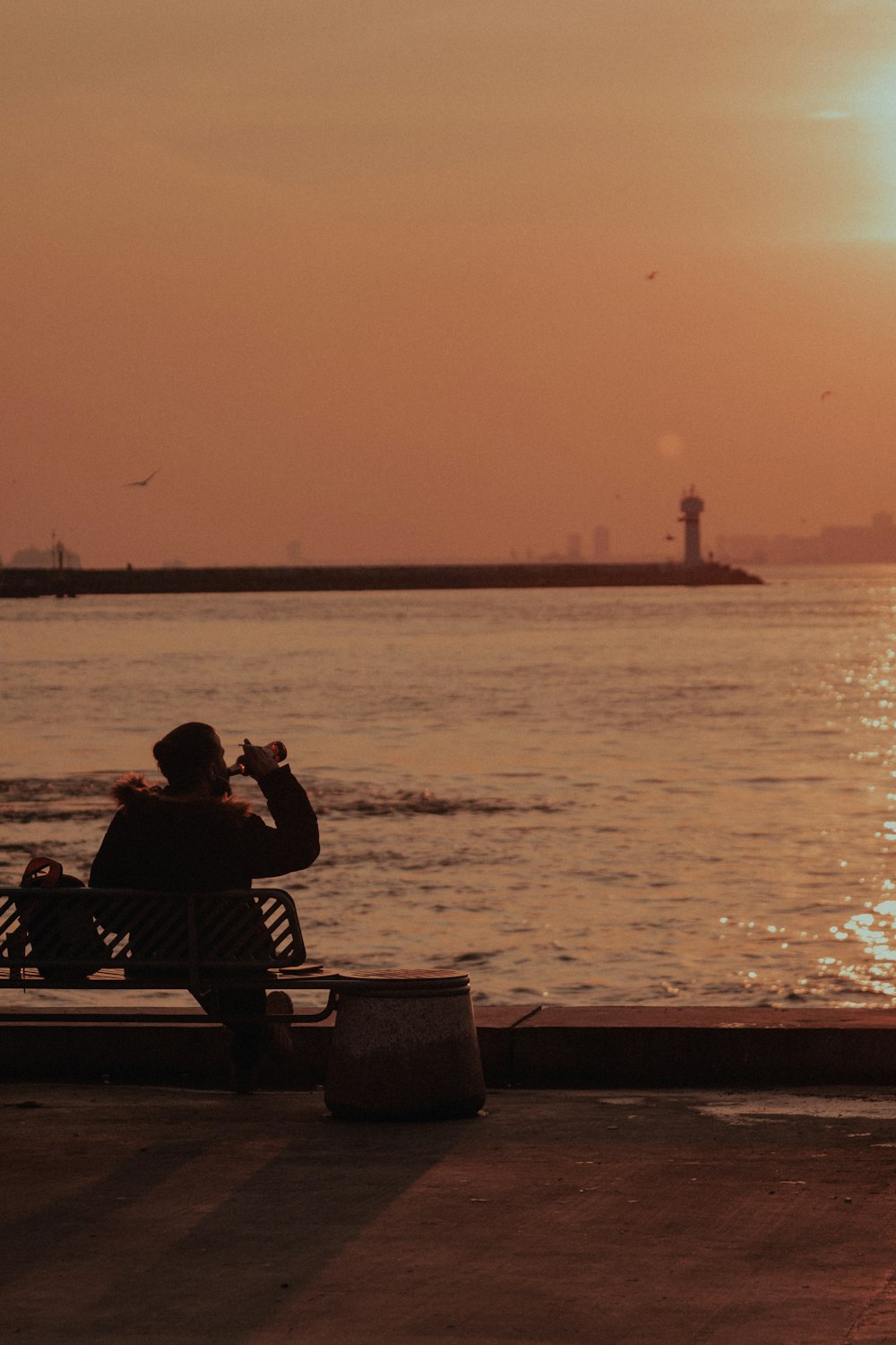 a person sitting on a bench near the water