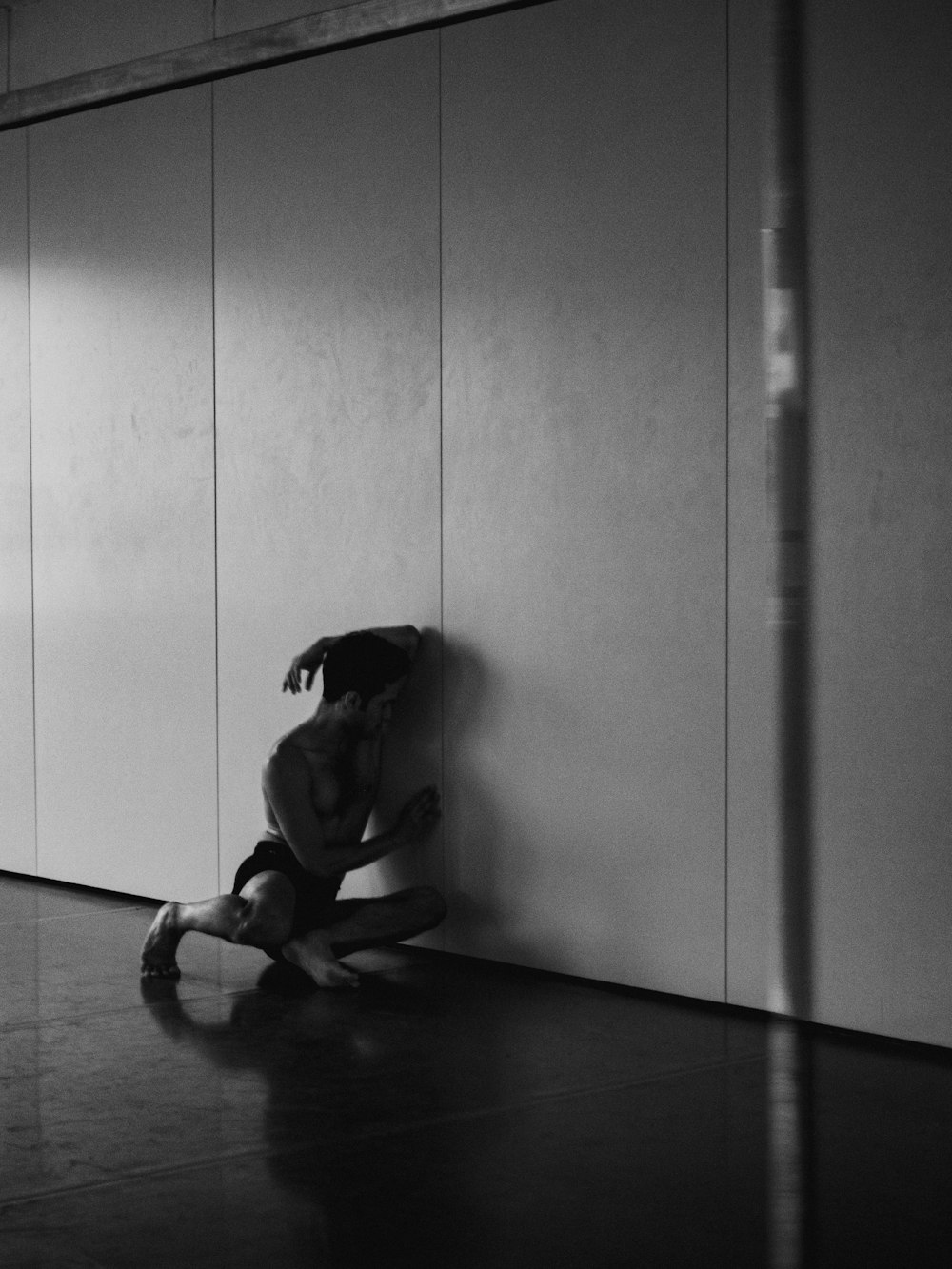 a woman sitting on the floor in front of a wall