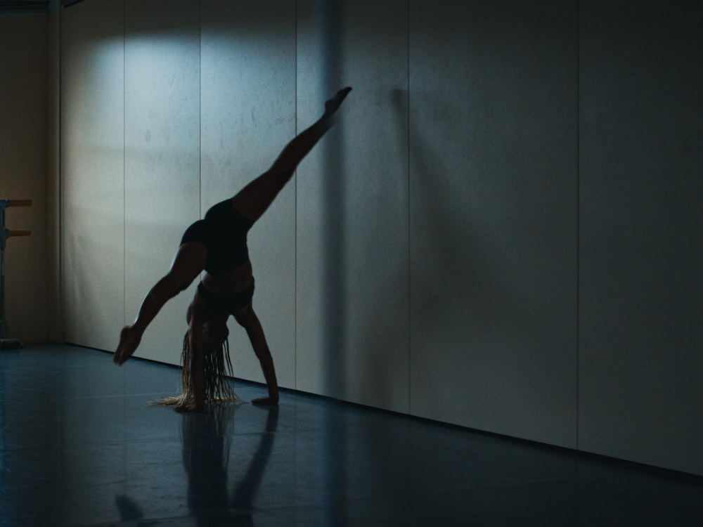 a woman doing a handstand in a dark room