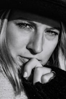 Close-up black and white image of a thoughtful face partially shadowed, eyes looking away.