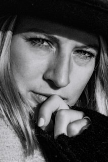 Close-up black and white image of a thoughtful face partially shadowed, eyes looking away.