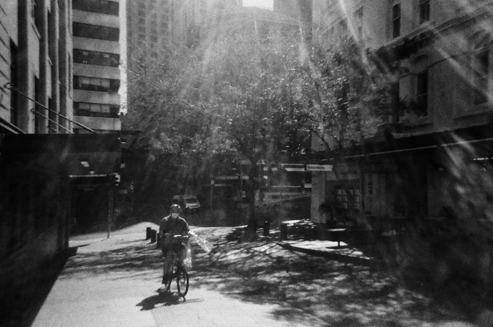 a man riding a bike down a street next to tall buildings