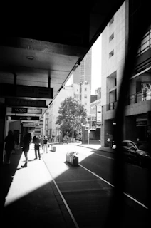 Black and white photo of an old city street lit by soft afternoon shadows.