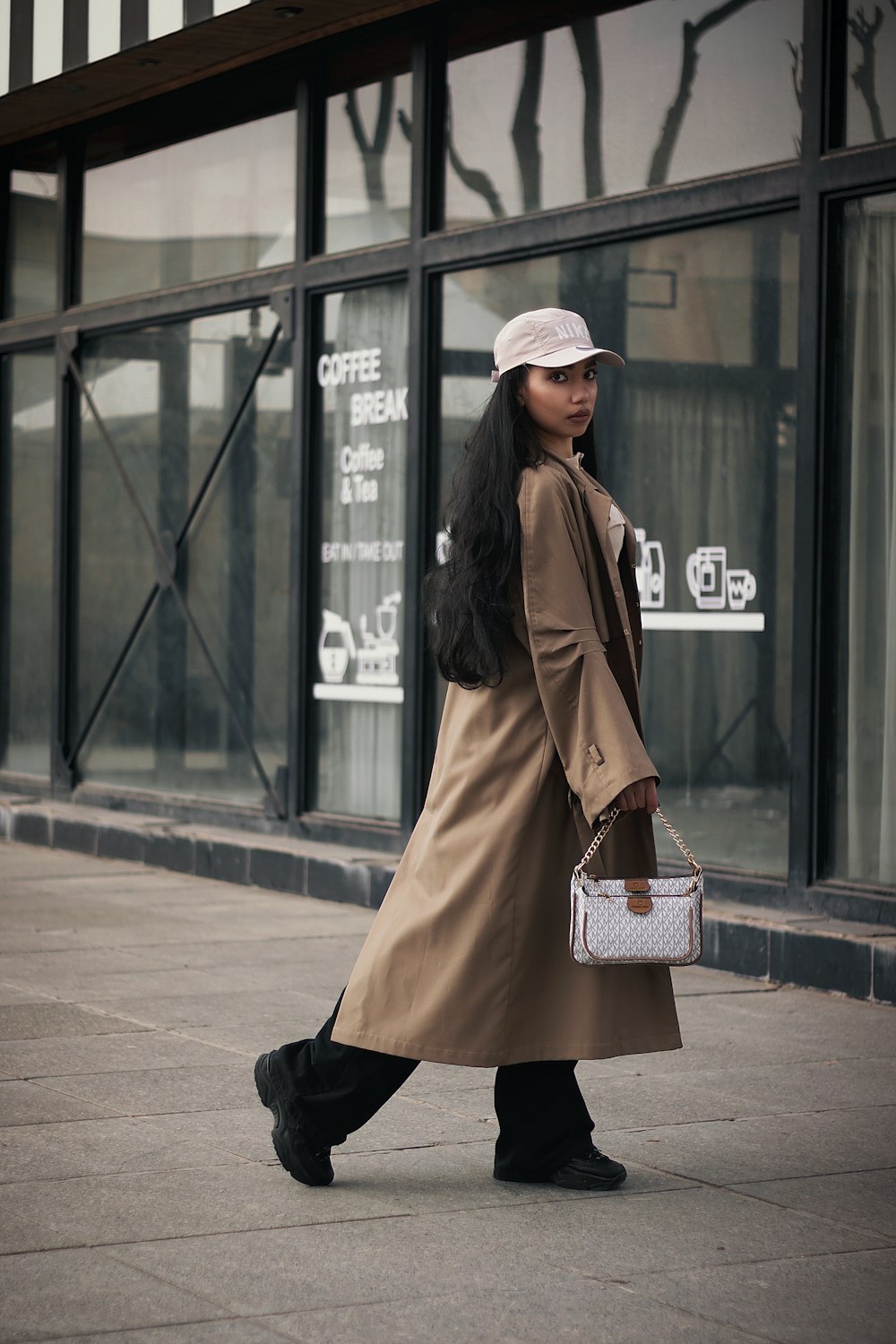a woman walking down a sidewalk carrying a purse