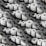 A large number of white paper rolls are tightly packed together, creating a uniform and repetitive pattern. Each roll has a circular hole in the center, and they are arranged in various orientations, contributing to the overall texture and visual interest.