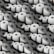 A large number of white paper rolls are tightly packed together, creating a uniform and repetitive pattern. Each roll has a circular hole in the center, and they are arranged in various orientations, contributing to the overall texture and visual interest.