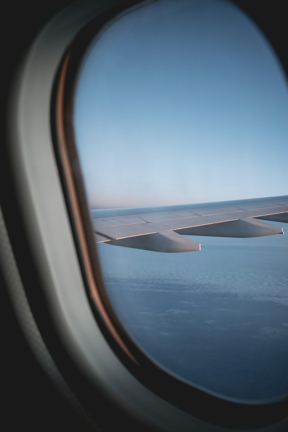 a view of the wing of an airplane as it flies over the ocean