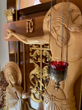 Close-up of a detailed lamp base featuring Christian symbols carved in wood.