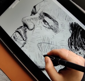 a person is drawing on a tablet with a pen