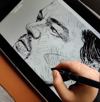 a person is drawing on a tablet with a pen