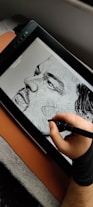 a person is drawing on a tablet with a pen
