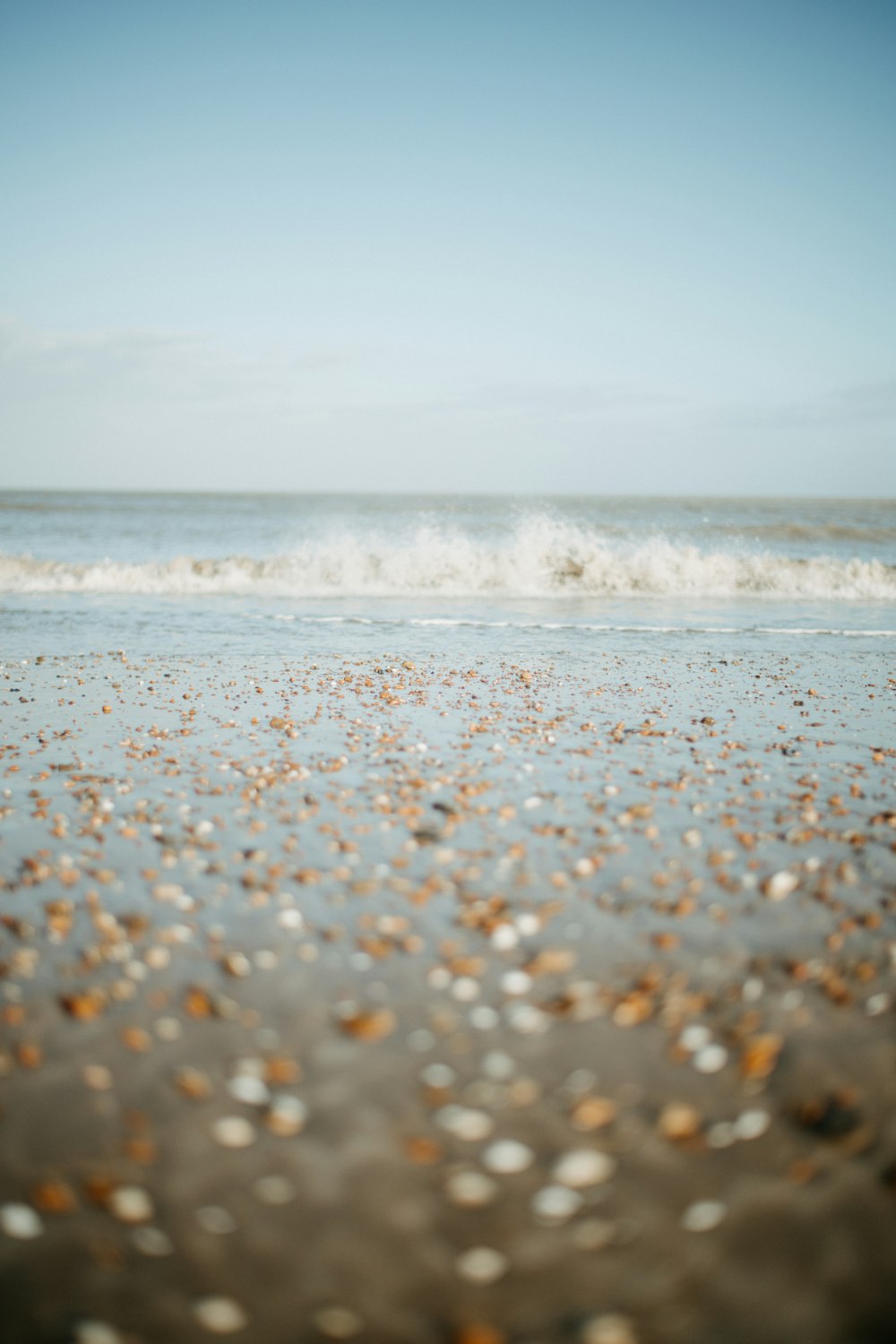 a sandy beach with a wave coming in to shore