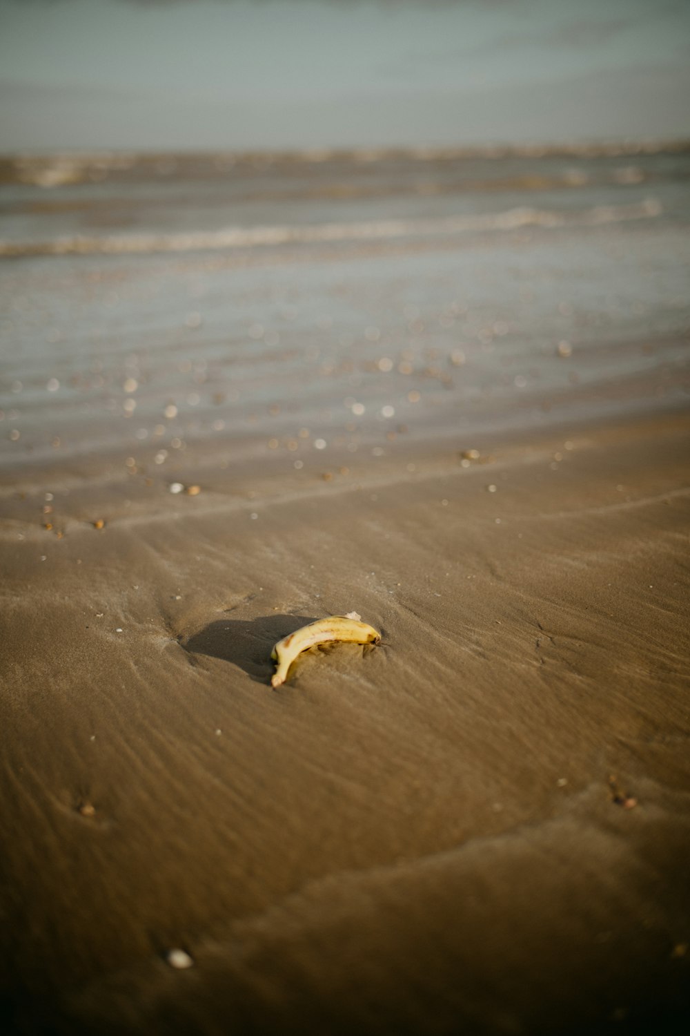 a half eaten banana sitting on top of a sandy beach