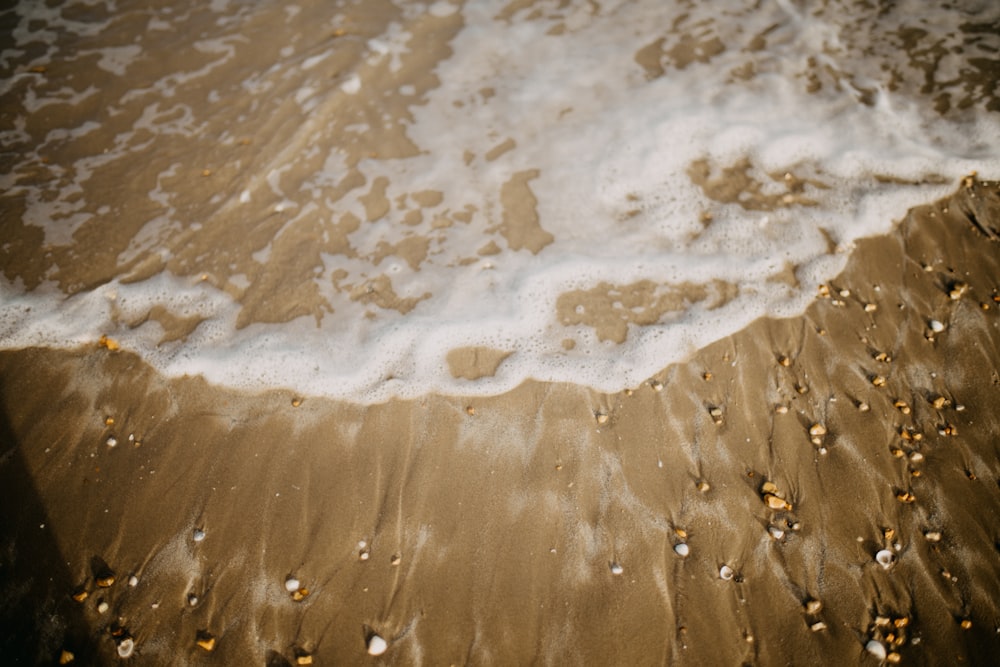 a sandy beach with a wave coming in to shore