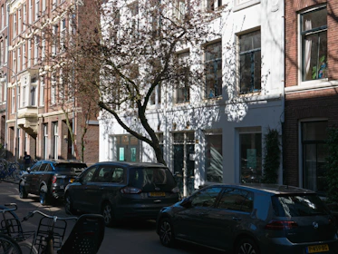 cars parked on the side of a street next to tall buildings