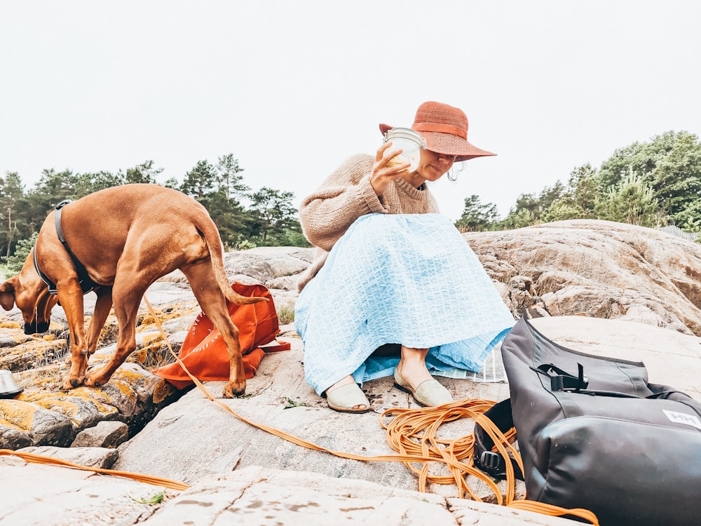 a woman sitting on a rock next to a dog