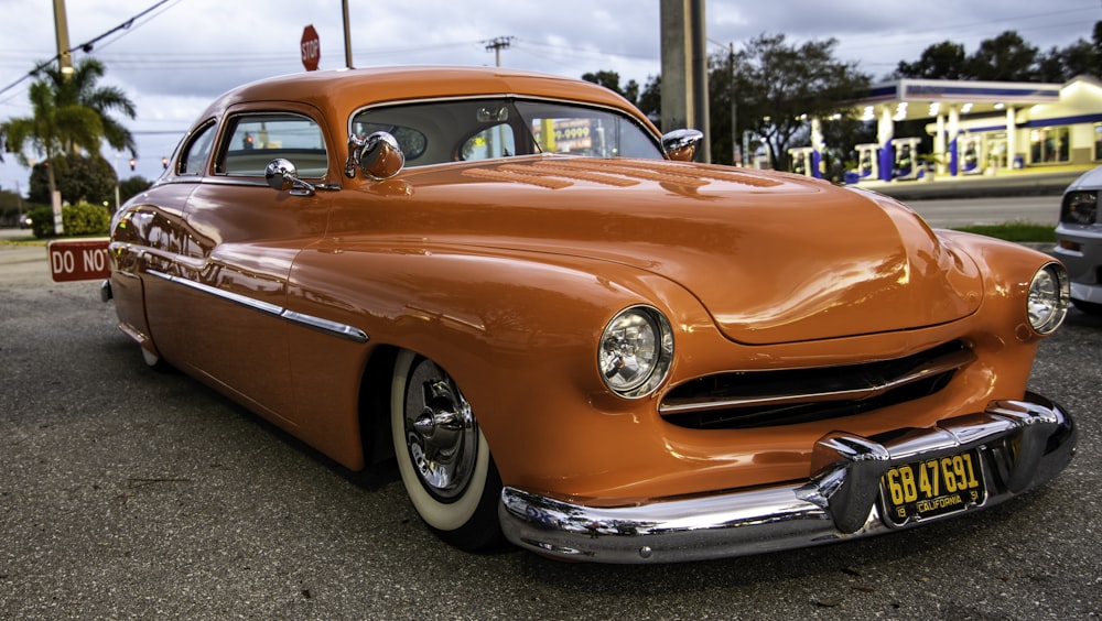 an orange classic car parked in a parking lot