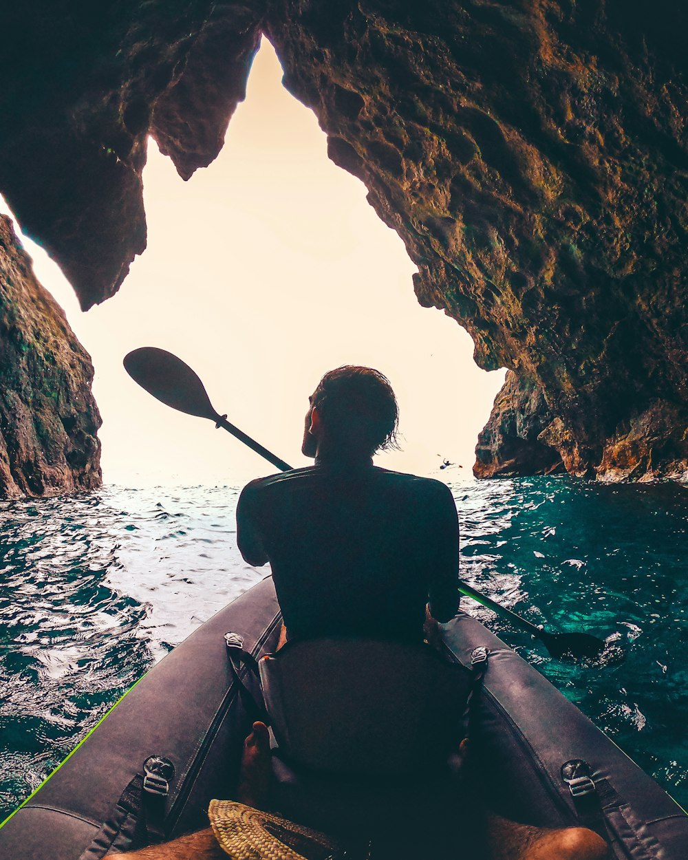 a person in a kayak in front of a cave