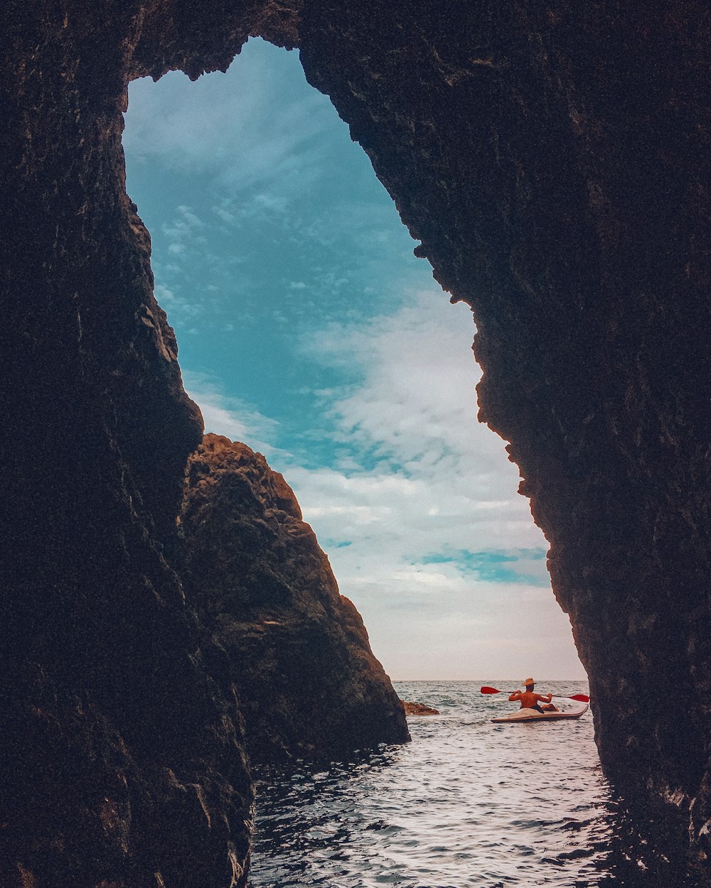 a person in a kayak in the water between two large rocks