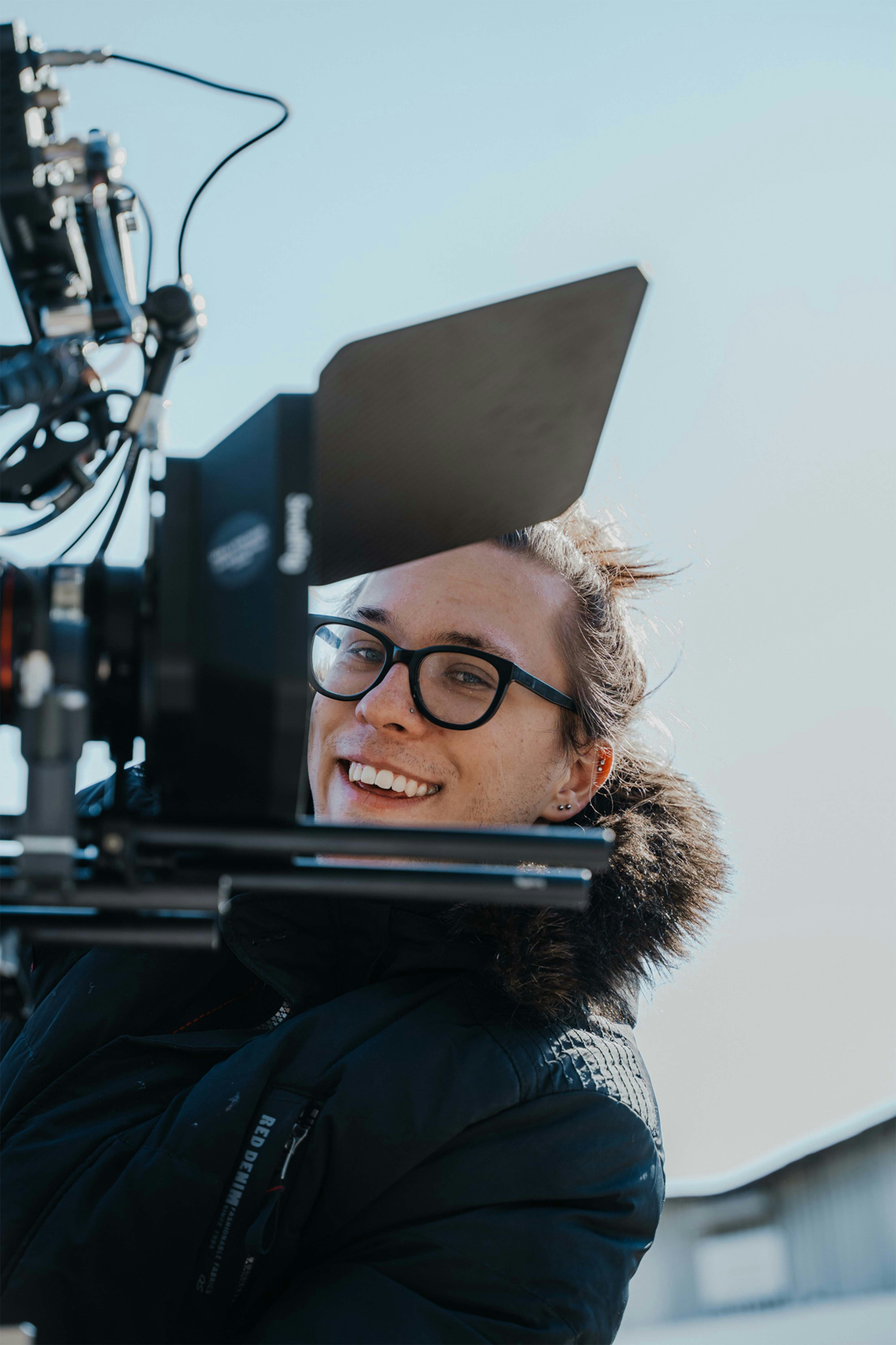 a woman in a black jacket and glasses standing in front of a camera