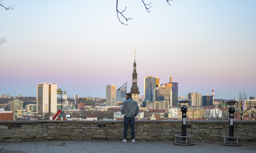a man standing on a stone wall with a city in the background
