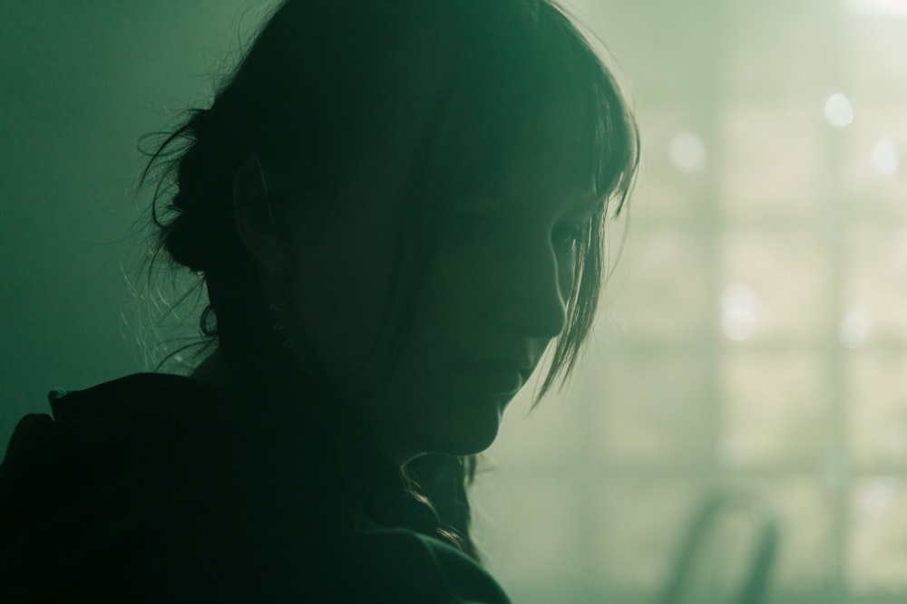 a person with long hair standing in a dark room