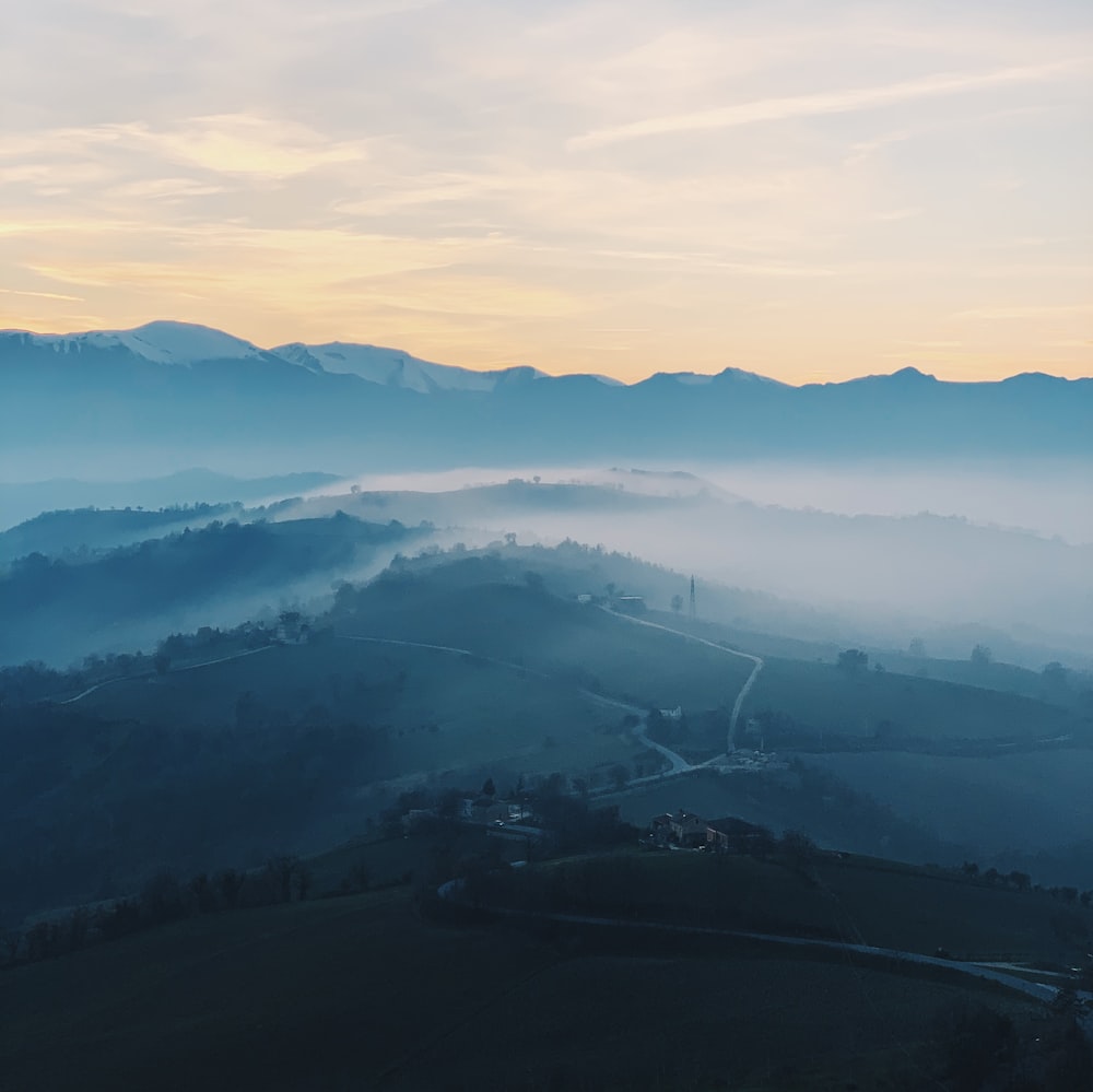 a view of a foggy valley with mountains in the background