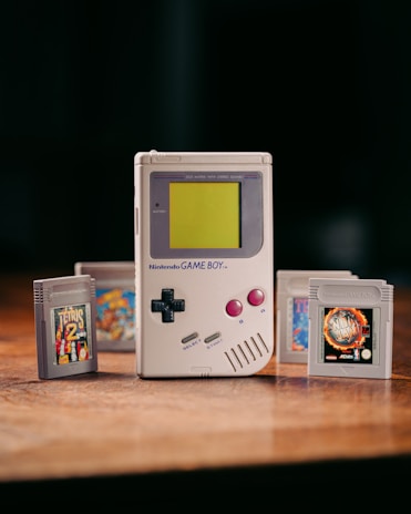 An original Game Boy console alongside a stack of retro game cartridges.