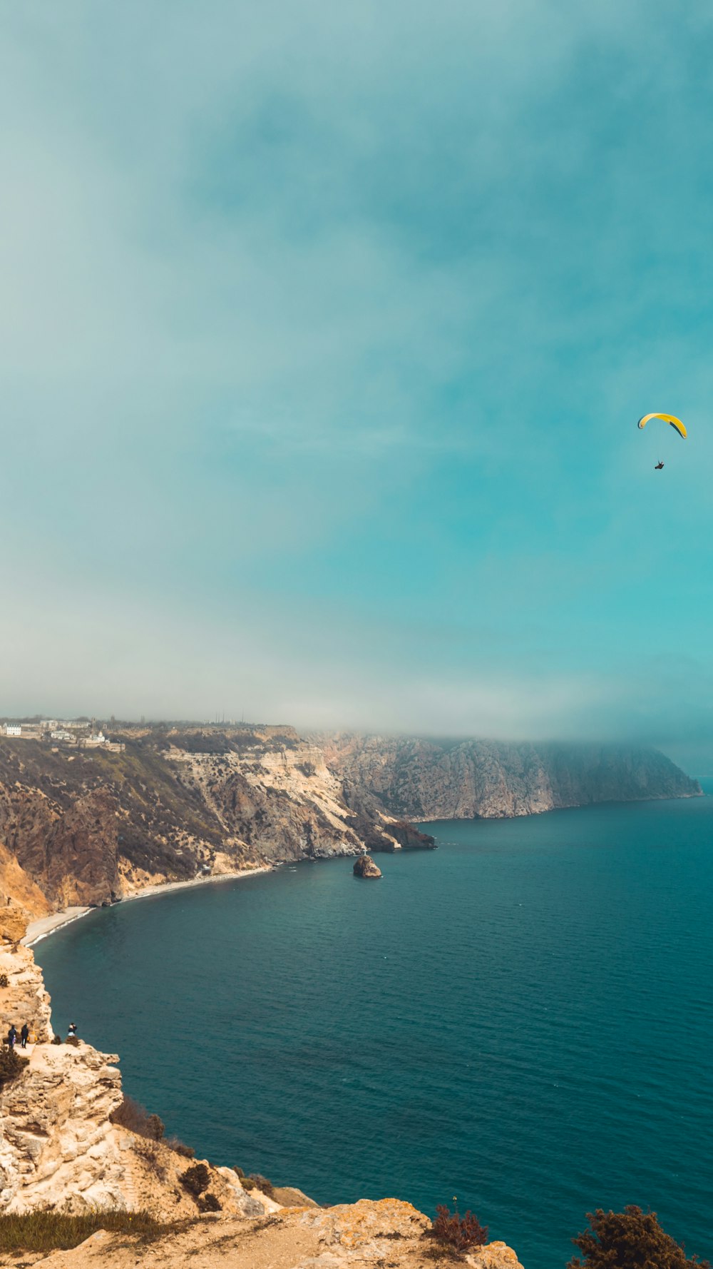a paraglider flying over a large body of water