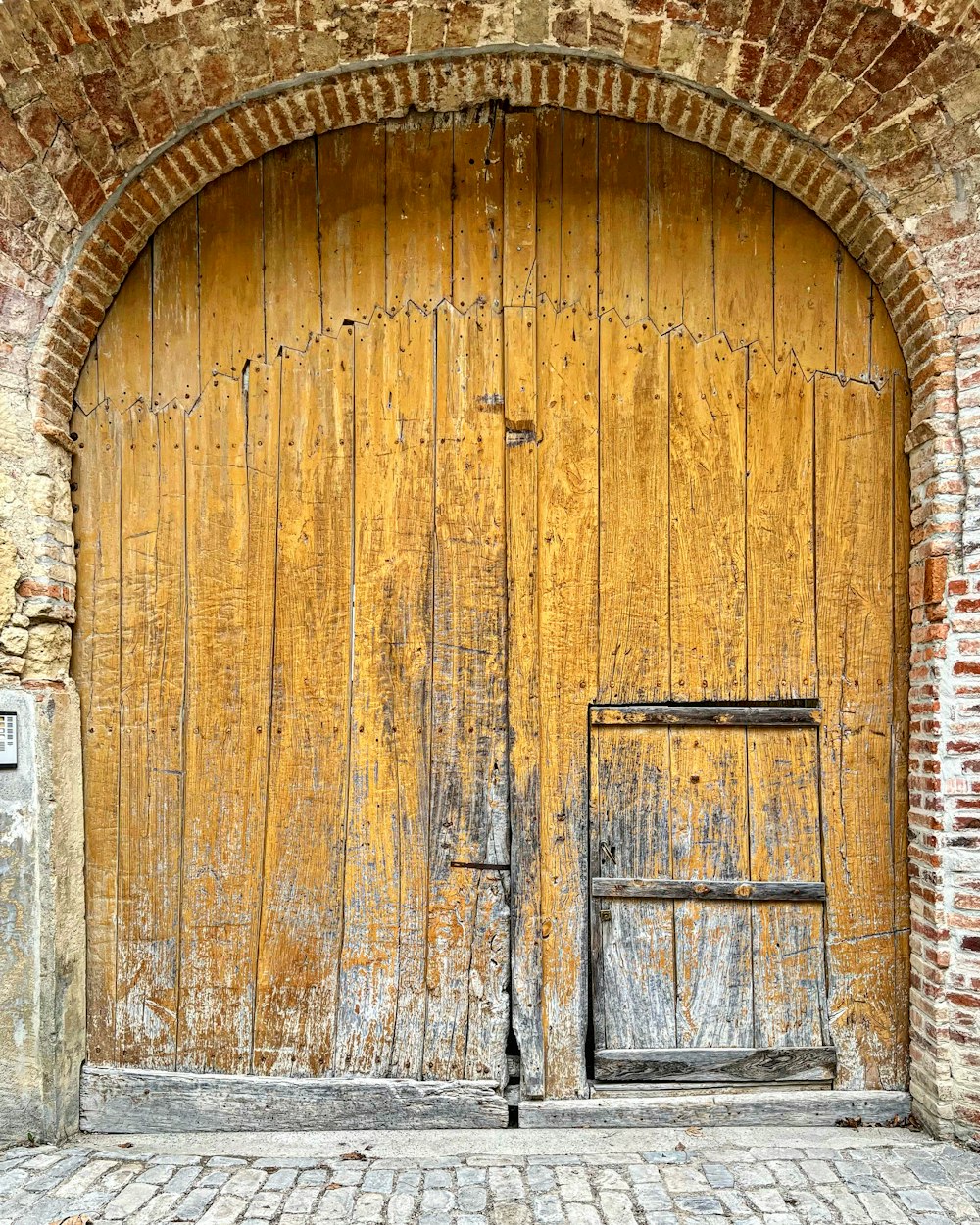 a wooden door with a brick wall behind it