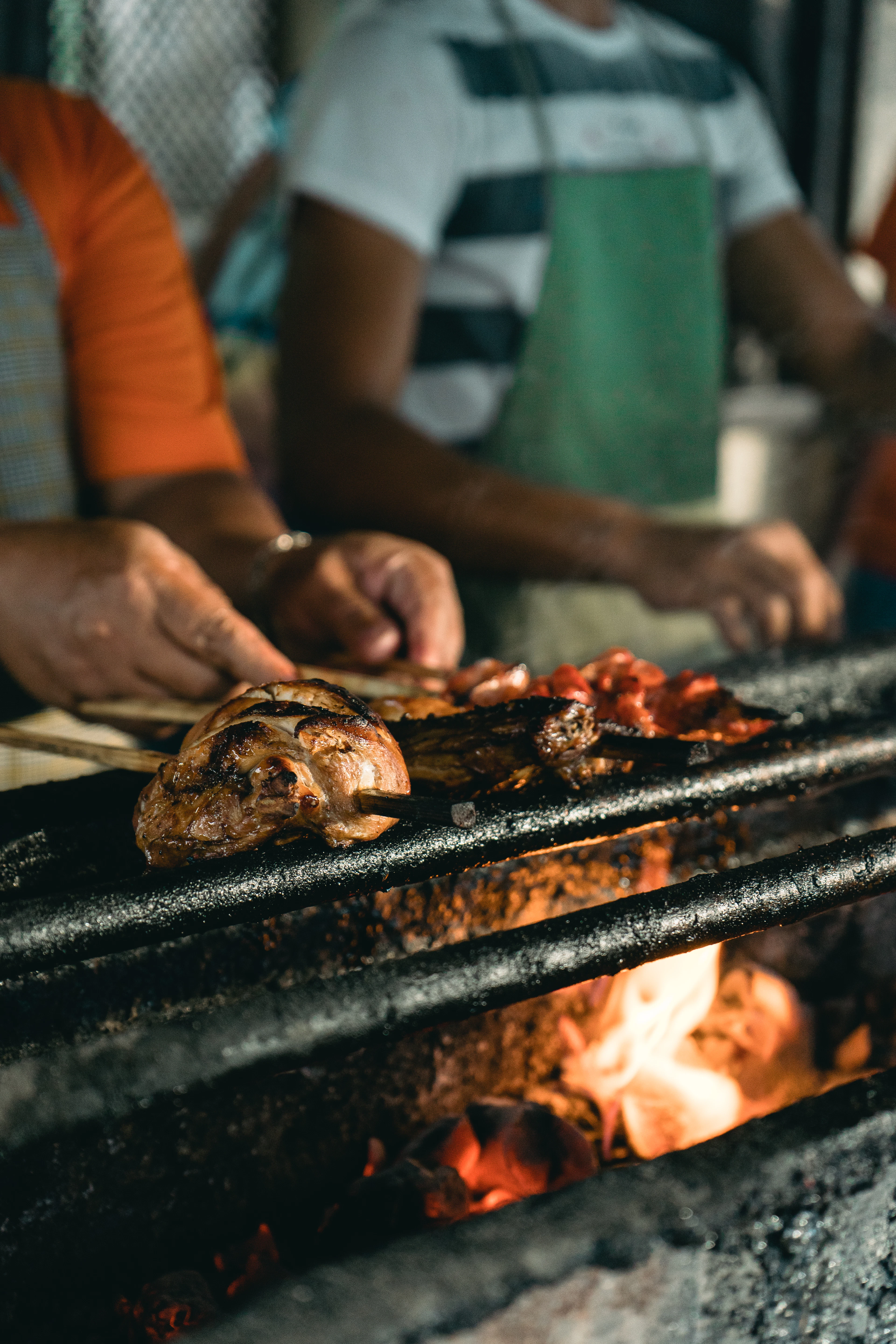 A vendor turning skewers of marinated meat over an open charcoal fire at a street grill in Cebu, Philippines