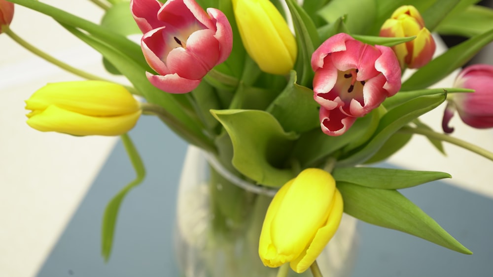 a vase filled with lots of pink and yellow flowers