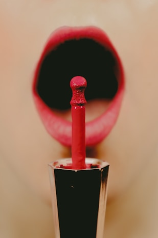 Close-up of a makeup artist applying lipstick in a bright, cozy salon setting.