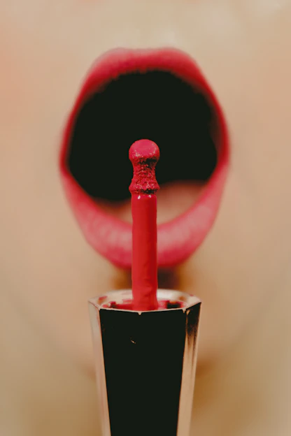 Close-up of a smiling woman applying vibrant lipstick in a bright, modern bathroom.